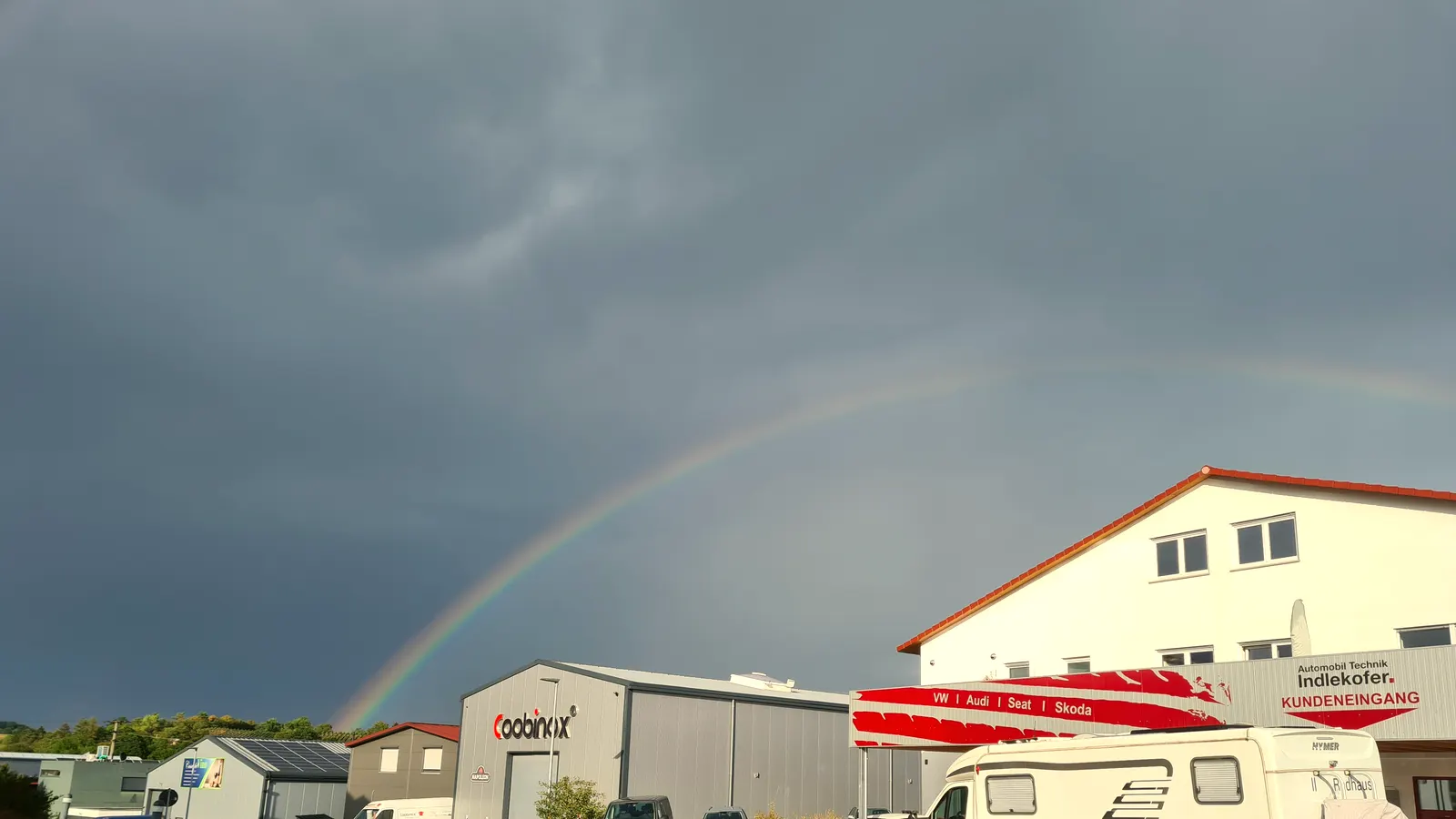 Das Werkstattgebäude von Automobil Technik Indlekofer unter einem Regenbogen in Steinheim an der Murr.
